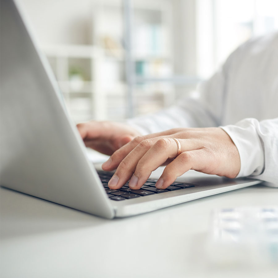 Arzt nutzt Laptop zur Abrechnung von Hybrid-DRG-Leistungen und tippt etwas via Tastatur ein