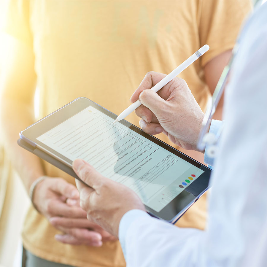 Mediziner gibt etwas in eine digitale Software auf einem Tablet ein. Vermutlich geht es um die Dokumentation oder Zuordnung von medizinischen Leistungen
